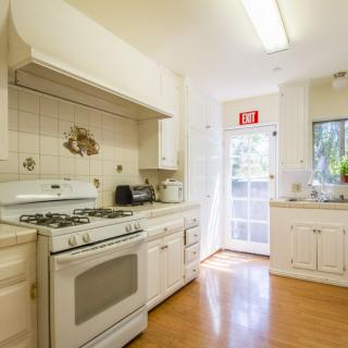 A bright, cozy kitchen with white cabinets and a gas stove.
