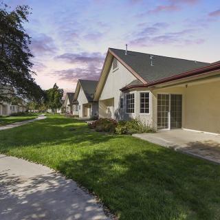 A peaceful suburban neighborhood with houses, green lawns, and a winding pathway at sunset.