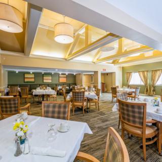 A warmly lit dining room with neatly arranged tables and chairs, featuring elegant decor and soft lighting.