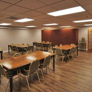 A well-lit conference room with multiple tables and chairs arranged for meetings.