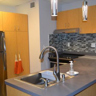 A modern kitchen with a stainless steel sink and appliances, complemented by wooden cabinets and a stylish backsplash.