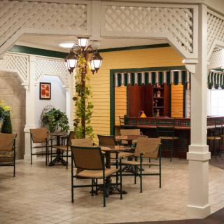 An indoor cafe setting with tables, chairs, and decorative elements such as plants and pendant lighting.