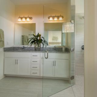 A modern bathroom featuring a glass-enclosed shower, double vanity with mirrors, and stylish lighting.