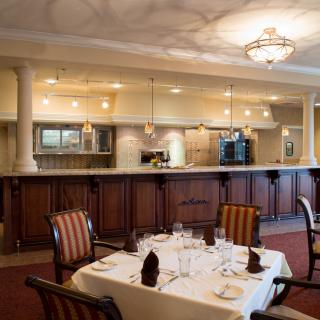 A cozy restaurant interior showcasing a well-set dining table and an open kitchen view.