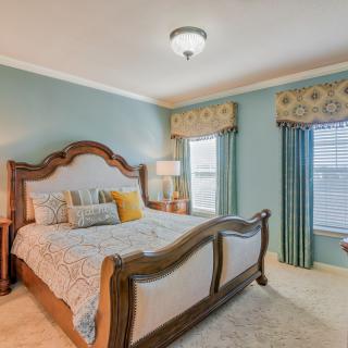 A well-decorated bedroom with a large wooden bed, stylish bedding, and coordinated curtains.