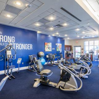 A modern gym with various exercise machines and motivational decor.