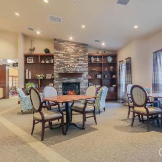 A cozy dining area with elegant seating and a fireplace, surrounded by bookshelves.