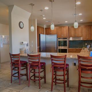 A modern kitchen featuring stainless steel appliances, wood cabinets, and an island with bar stools.