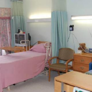 A hospital room with a bed, medical equipment, and curtains for privacy.