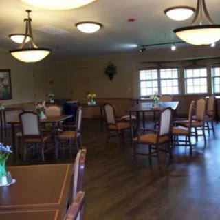 A spacious dining area with several tables and chairs, illuminated by overhead lights.