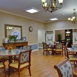 A well-decorated dining room with multiple tables and chairs, featuring chandeliers and elegant decor.