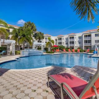 A beautiful resort-style pool area surrounded by lush greenery and sunny skies.