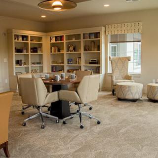 A modern conference room featuring a round table surrounded by comfortable chairs, with bookshelves lining the walls.