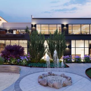 A modern house with large windows, surrounded by a landscaped garden featuring a fountain.