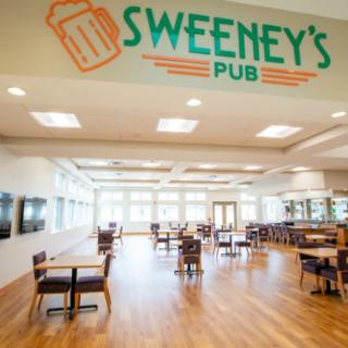 Interior view of Sweeney's Pub with wooden flooring and seating arrangements.