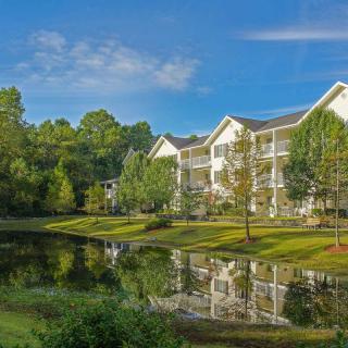 A serene residential apartment complex by a tranquil lake surrounded by lush greenery.