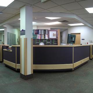 A panoramic view of a modern reception area in an office, showcasing the front desk and workspace.