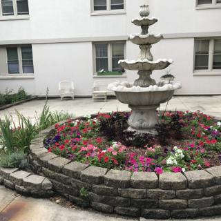 A beautiful courtyard garden with a multi-tiered fountain surrounded by colorful flowers.