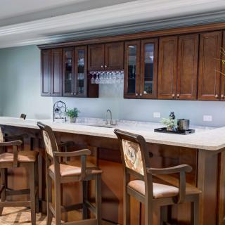 A modern kitchen interior featuring a bar counter with wooden bar stools and elegant cabinets.