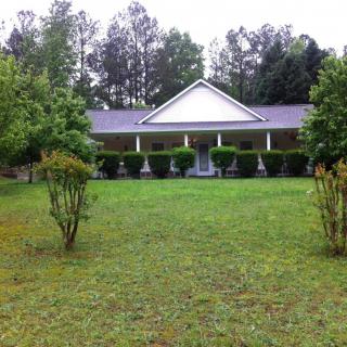 A house with a large front lawn and surrounding trees.