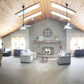 A spacious living room with a vaulted ceiling, skylights, and a cozy fireplace.