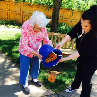 Two women engaging in an outdoor activity with a bucket.