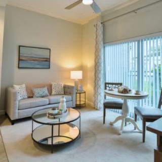 A cozy and modern living room with a sofa, coffee table, and a small dining area by the window.