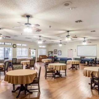 A spacious dining area with round tables and chairs, ceiling fans, and ample lighting.