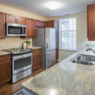 A modern kitchen with granite countertops, stainless steel appliances, and wooden cabinets.