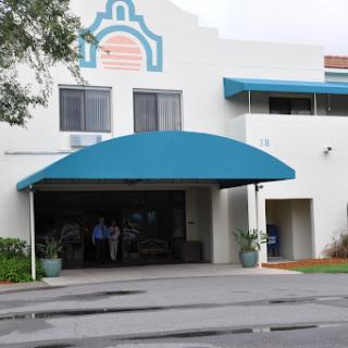 A modern commercial building featuring a prominent blue awning and unique architectural details.