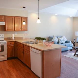 Open concept kitchen and living room with wooden cabinets and pendant lighting.