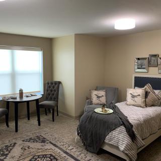 A cozy and modern bedroom with a small seating area featuring a table and two chairs, illuminated by soft lighting.