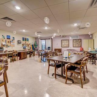 A cozy dining area with neatly arranged tables and chairs, decorative lighting, and a welcoming atmosphere.