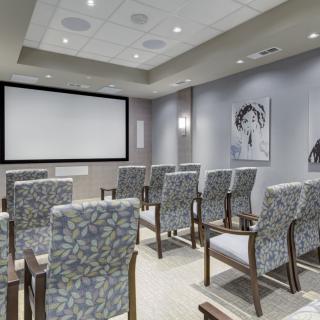A conference room with arranged seating and a large projector screen, ready for a meeting or presentation.