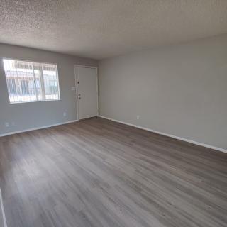 An empty room with hardwood flooring and natural light coming through a window.