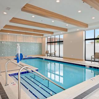 A modern indoor swimming pool with wooden ceiling beams and large windows.