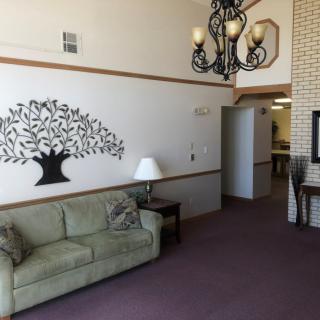 A cozy living room with a light green sofa, decorative wall art, and an elegant chandelier.