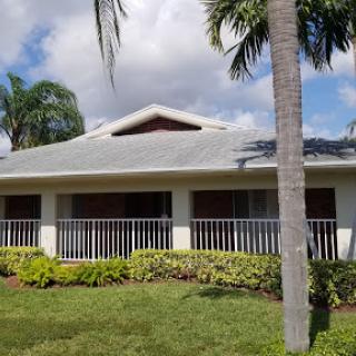 A charming residential house surrounded by palm trees and a well-maintained garden.