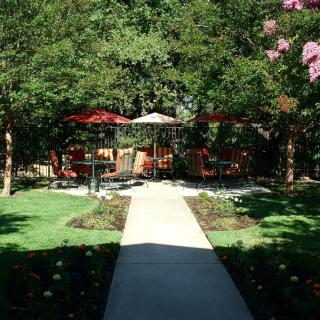 A serene garden with a pathway leading to an outdoor seating area under umbrellas.