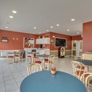 A brightly lit cafe interior with several empty tables and chairs arranged neatly.
