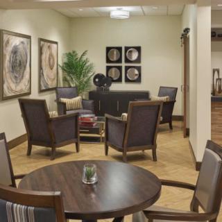 A cozy waiting room with stylish chairs, a small table, and decorative artwork on the walls.