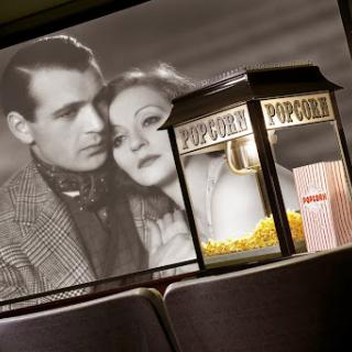 A nostalgic moment captured in a vintage cinema setting, featuring a black and white film scene alongside a classic popcorn machine.