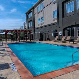 A tranquil hotel pool surrounded by comfortable lounge chairs, perfect for a sunny afternoon.