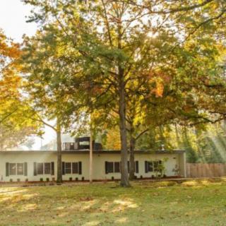 A serene house surrounded by trees with sunlight filtering through the branches.