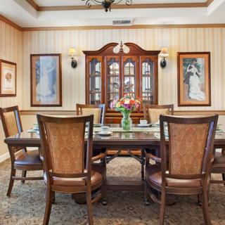 An elegant dining room with a large table, chairs, and a decorative cabinet.