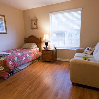 A cozy bedroom with a single bed, a couch, and a window allowing natural light.