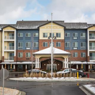 A multi-story hotel building with a covered entrance and parked cars, surrounded by snow.