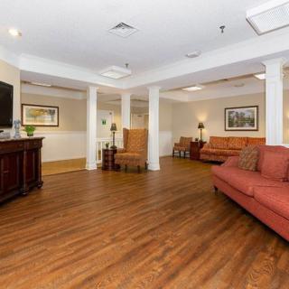 A cozy living room with wooden flooring, sofas, and ceiling lights.