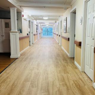 A well-lit corridor featuring wooden flooring and multiple doors leading to different rooms.