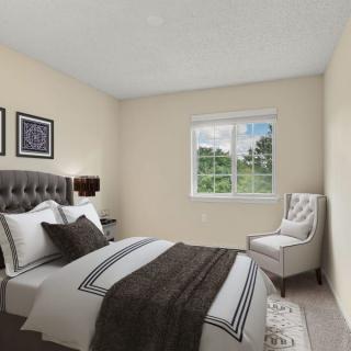 A cozy bedroom with a neatly made bed, featuring neutral colors and a window with a view.